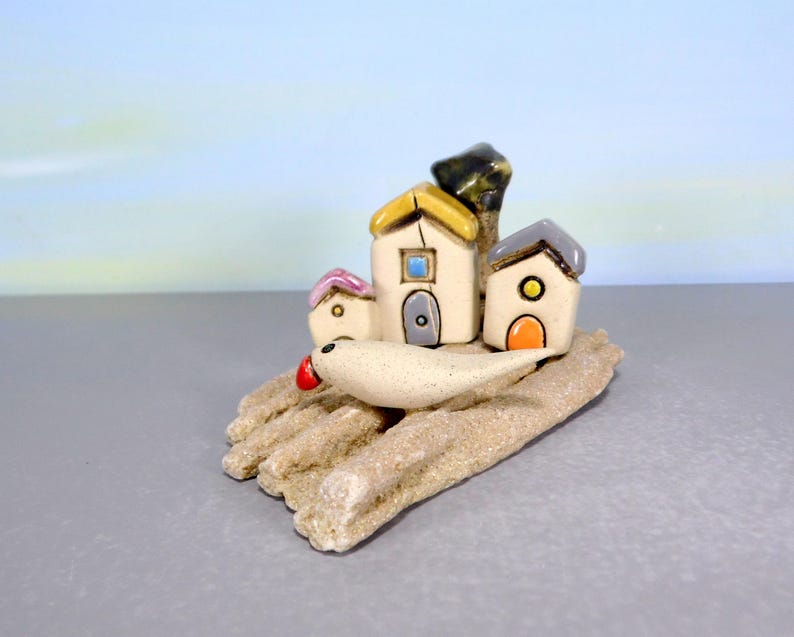 Whimsical white miniature ceramic houses with anOlive tree on a unique beach stone image 2