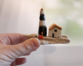 Miniature house and a lighthouse with a bird, on a natural Mediterranean beach stone, Beach house decor