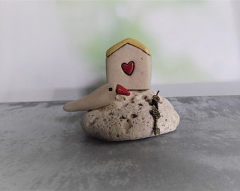 Miniatur-Keramik-Haus mit einem Ton Vogel und einen winzigen Schlüssel auf einem natürlichen StrandStein, Geschenk der Liebe