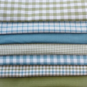 May include: A stack of eight fabric squares in various shades of green and blue with a checkered pattern. The fabric squares are folded neatly on top of each other.