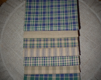 Puede incluir: Pila de ocho cuadrados de tela en varios patrones de cuadros. Las telas son una mezcla de marrón claro, verde y azul.