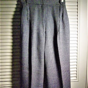 May include: Black and white houndstooth patterned pants with pleats.