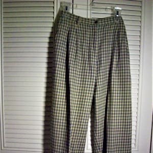 May include: A pair of plaid pants with a light brown and dark green checkered pattern. The pants have pleats at the waist and a button fly.