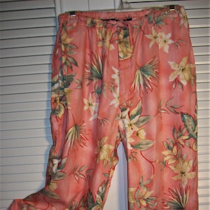 May include: A pair of wide-leg pants with a floral print in shades of pink, green, and white. The pants have an elastic waistband and a relaxed fit.