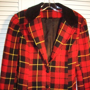 May include: A red, black, and yellow plaid jacket with a black velvet collar. The jacket has a button closure and two pockets.