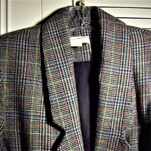 May include: A plaid blazer with a black collar and a black lining. The blazer has a multi-colored plaid pattern with shades of blue, green, red, and white.