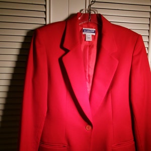 May include: A red blazer with a single button closure and a pocket on each side. The blazer has a label that reads "Pendleton".
