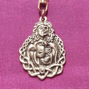 May include: A silver-toned keychain featuring a detailed sculpture of two figures intertwined. The figures are surrounded by a Celtic knot design.
