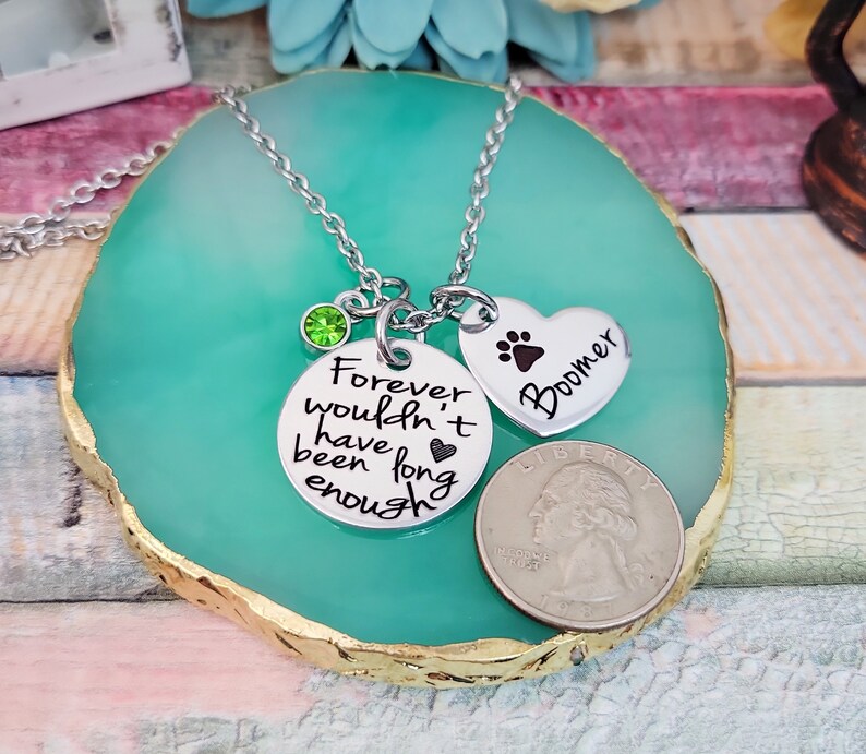 May include: Silver necklace with a green crystal charm, a round charm with the text "Forever wouldn't have been long enough" and a heart charm with a paw print and the text "Boomer".