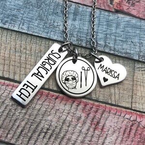 May include: Silver necklace with three charms. The first charm is a rectangular tag with the text "SURGICAL TECH". The second charm is a round charm with a drawing of a person wearing a surgical cap and mask, and surgical scissors. The third charm is a heart-shaped charm with the name "MARISSA" engraved on it.
