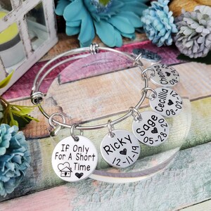 May include: Silver charm bracelet with six charms. The charms are round and have names and dates engraved on them. The charms read "Ricky 12-11-19", "Sage 05-28-20", "Cecillia 08-02-21", "Chenog 08-29-22", and "If Only For A Short Time".