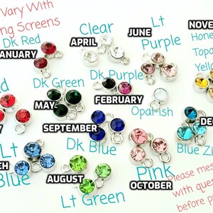 May include: A set of 12 charm pendants featuring a different colored crystal for each month of the year. The charms are silver with a loop for attaching to a bracelet or necklace. The crystals are clear, red, green, purple, blue, pink, yellow, and topaz.