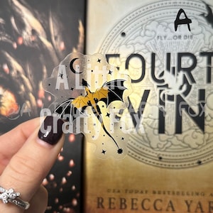 May include: A clear sticker with a gold and black dragon flying through a field of stars. The sticker says "A Little Fourt" and has a crescent moon in the upper left corner.