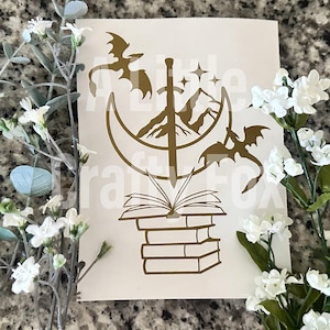 May include: Gold vinyl decal featuring a crescent moon, a sword, mountains, stars, a dragon, and a stack of books. The design is reminiscent of a fantasy book cover.