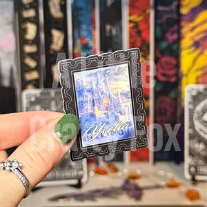 Può includere: Un adesivo bianco e nero con un bordo decorativo. L'adesivo presenta un'illustrazione blu e bianca di un castello con il testo "Yrellia" e "20165" stampato su di esso.