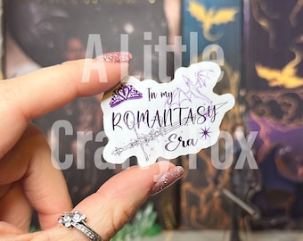 May include: A white sticker with a purple crown, a sword, a dragon, and the text "In my RomanTasy Era*" in purple lettering.