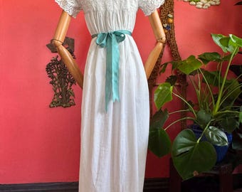 1900s white gown with lace details and blue ribbons.
