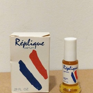 May include: A vintage perfume bottle and box set. The box and bottle feature the name "Réplique" with blue and red accents. The bottle contains a golden liquid and has a white cap. The box reads 29 FL. OZ.