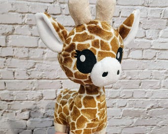 Könnte beinhalten: Ein Plüsch-Giraffe-Spielzeug mit braunen und weißen Flecken. Die Giraffe hat große schwarze Augen und ein weißes Gesicht. Das Spielzeug steht auf einer Hand.