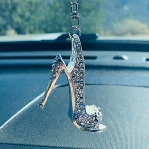 May include: A silver high heel shoe charm with rhinestones, hanging from a clear crystal and silver chain.