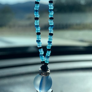 May include: A blue and black beaded car charm with a clear glass orb and silver accents.