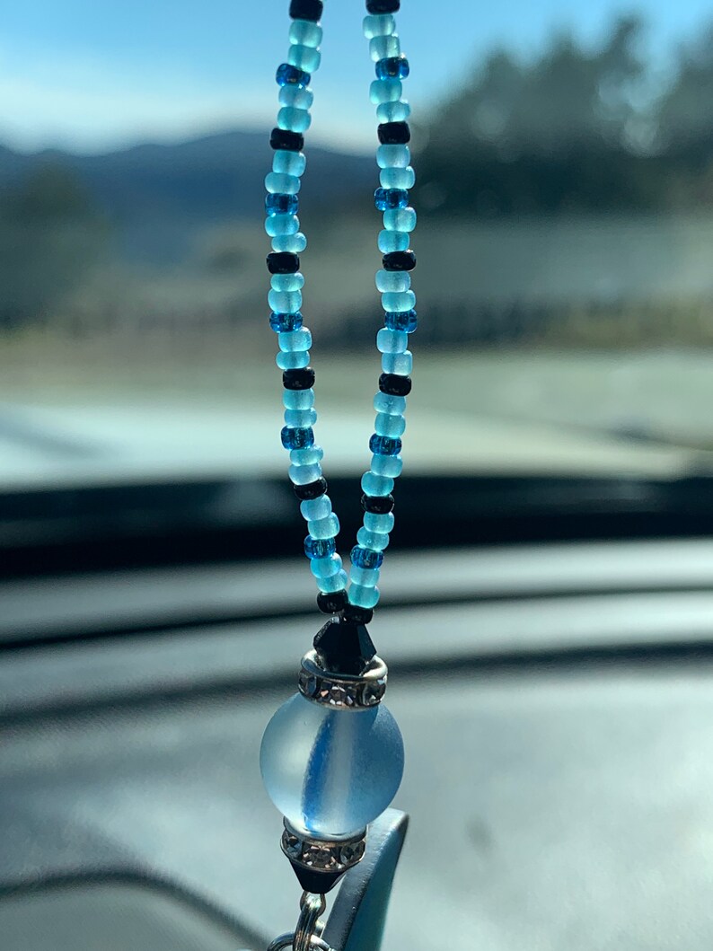 May include: A blue and black beaded car charm with a clear glass orb and silver accents.
