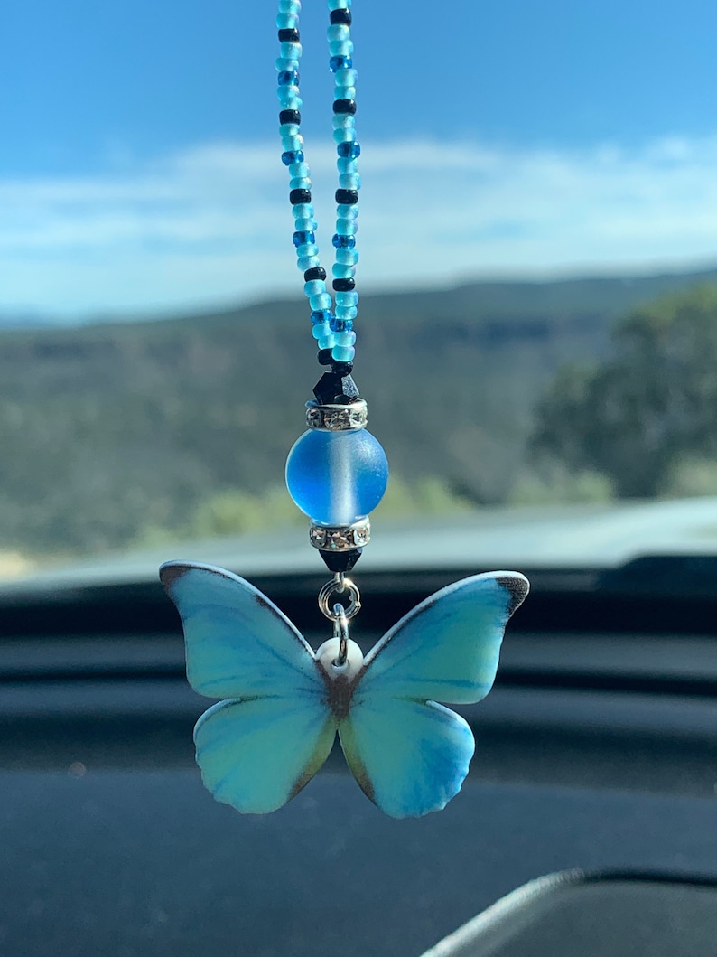 May include: A blue butterfly car charm with a beaded chain and a blue and silver bead.