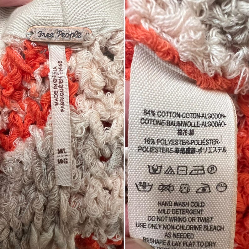 Może przedstawiać: Zbliżenie na dzianinowy element garderoby Free People. Ubranie to mieszanka kolor&oacute;w pomarańczowego, kremowego i szarego. Etykieta głosi "MADE IN CHINA" oraz "84% COTTON" i "16% POLYESTER". Ubranie ma teksturowany, otwarty splot.
