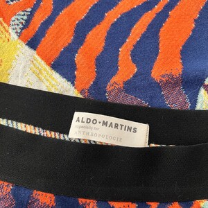 Puede incluir: Una tela de rayas blancas y negras con un patr&oacute;n abstracto azul y naranja. La tela tiene una etiqueta que dice "ALDO MARTINS especially for ANTHROPOLOGIE".