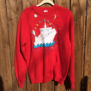 May include: Red sweatshirt with a colorful illustration of a cruise ship with the text "Fair Princess" on the front.
