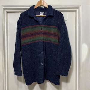 Peut inclure: Une chemise boutonnée en fourrure bleu foncé avec un motif rayé multicolore sur la poitrine.