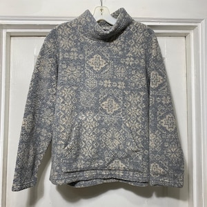 May include: A grey and white patterned fleece pullover with a mock neck and a kangaroo pocket.