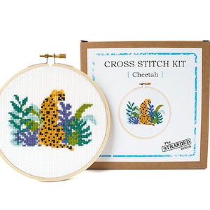 May include: Cross stitch kit featuring a cheetah in a jungle setting. The kit includes a hoop, fabric, floss, and instructions. The box is brown with the text "CROSS STITCH KIT {Cheetah} The STRANDED Stitch"