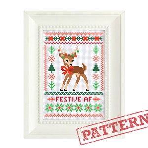 May include: A framed cross-stitch pattern featuring a reindeer with a red bow and festive decorations. The design includes green Christmas trees and red and green floral patterns. The text "FESTIVE AF" is displayed in green and white.