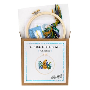 May include: A cross stitch kit featuring a cheetah in a jungle setting. The kit includes a wooden embroidery hoop, Aida cloth, embroidery floss, and a needle. The box is brown with the text "CROSS STITCH KIT {Cheetah} The STRANDED Stitch"