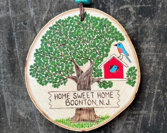 Bluebirds in a red birdhouse home sweet home wood slice ornament. Personalize the wooden sign with your town. Handmade by Forage Workshop