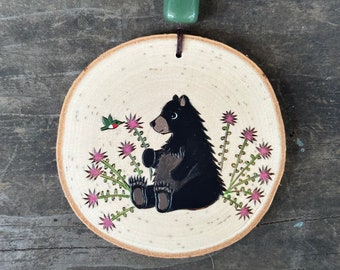 Black bear in a bee balm patch befriending a hummingbird on wood slice. Handcrafted ornament. Handmade by Forage Workshop PREORDER
