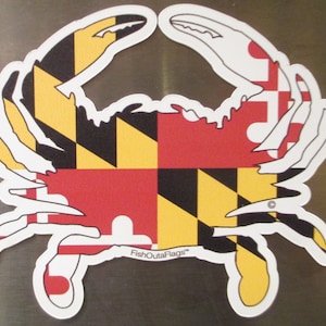 May include: A crab-shaped sticker featuring the Maryland state flag design. The sticker has a white outline and the crab's body is filled with the flag's black, yellow, red, and white pattern. The text "FishOutaFlags" is printed on the sticker.