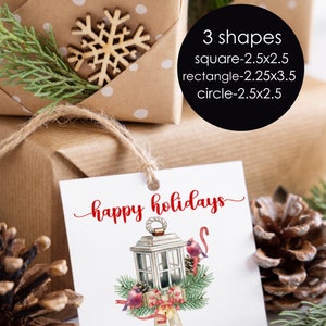 Puede incluir: Etiqueta de regalo blanca con texto rojo que dice "felices fiestas" y "de la familia Henderson". La etiqueta presenta una ilustración de acuarela de una linterna con cardenales rojos y una cinta roja.