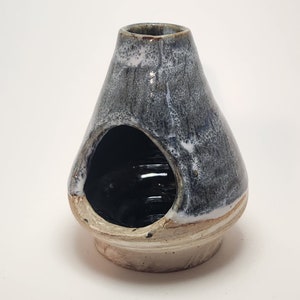 May include: A ceramic incense burner with a blue and white glaze. The burner has a large opening in the side and a smaller opening on the top.