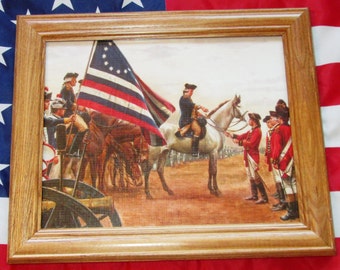 May include: A framed painting depicting a historical scene of a military surrender. A group of soldiers in red uniforms stand at attention while a general on horseback shakes hands with a soldier in blue. A large American flag with 13 stars is in the background.