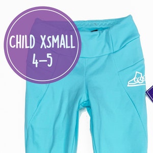 Könnte beinhalten: Eine hellblaue Leggings mit einem weißen Logo auf dem rechten Bein. Die Leggings ist mit "Child XSmall 4-5" gekennzeichnet.