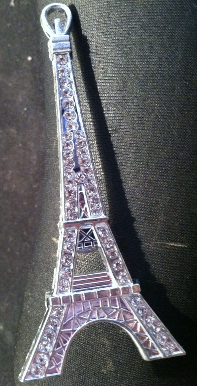 May include: A silver Eiffel Tower charm with rhinestones. The charm is a popular souvenir from Paris, France.