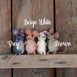 Op de afbeelding: Vier viltmuizen in verschillende kleuren: grijs, beige, wit en bruin. De muizen zitten op een houten oppervlak. De woorden "Beige White" en "Brown" staan boven de muizen.