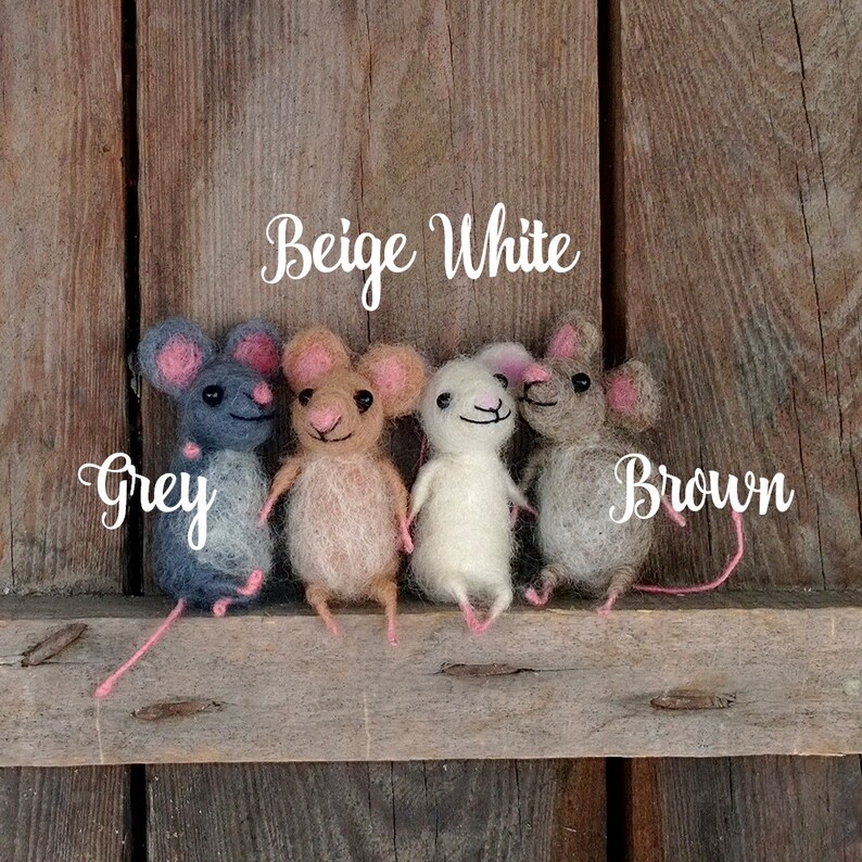 Op de afbeelding: Vier viltmuizen in verschillende kleuren: grijs, beige, wit en bruin. De muizen zitten op een houten oppervlak. De woorden "Beige White" en "Brown" staan boven de muizen.