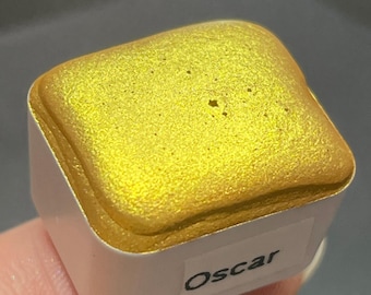 Puede incluir: Una bandeja cuadrada de pintura acuarela de color amarillo dorado con una etiqueta que dice "Oscar".