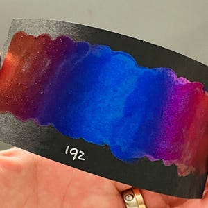 Op de afbeelding: Een zwarte kaart met een kleurverloop van rood, paars, blauw en roze. De kaart heeft het nummer 192 in wit.