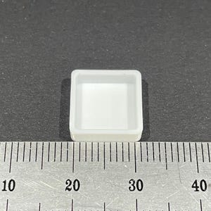 Pode incluir: Uma paleta de pintura quadrada de cerâmica branca com uma borda elevada. A paleta mede aproximadamente 6,5 cm de largura e 6,5 cm de comprimento.