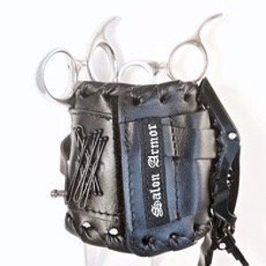 Puede incluir: Porta tijeras de cuero negro con dise&ntilde;o de guante de b&eacute;isbol. El porta tijeras tiene una correa con hebilla y el texto "Salon Armor" est&aacute; impreso en el lateral.