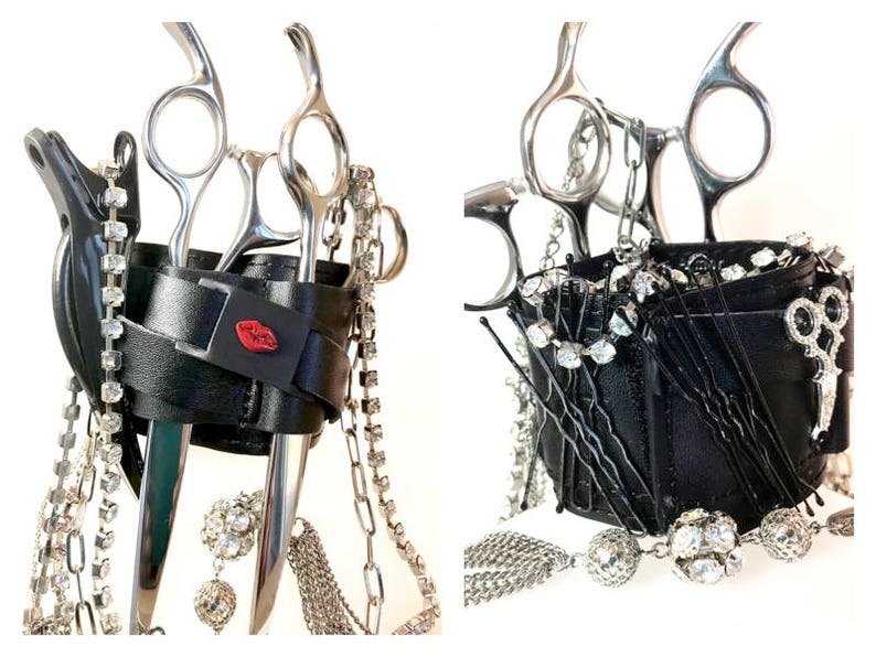 May include: Black leather scissor holder with silver chains and rhinestones. The holder has two slots for scissors and a small pocket. There is a red lip design on the front of the holder.